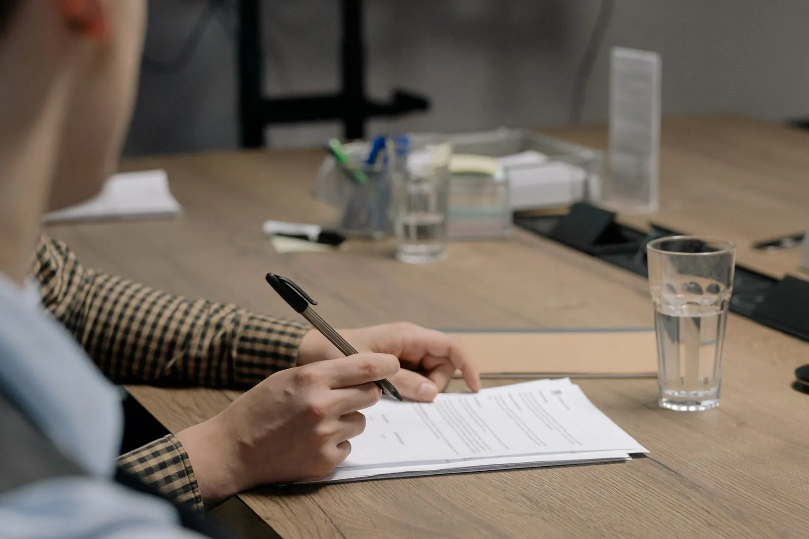 A person signing legal documents at a desk in an office